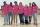 Six adolescents et adolescentes et une femme d'âge moyen, se tenant debout les bras les uns autour des autres, sourient vers l'objectif. Tous et toutes portent des t-shirts roses.